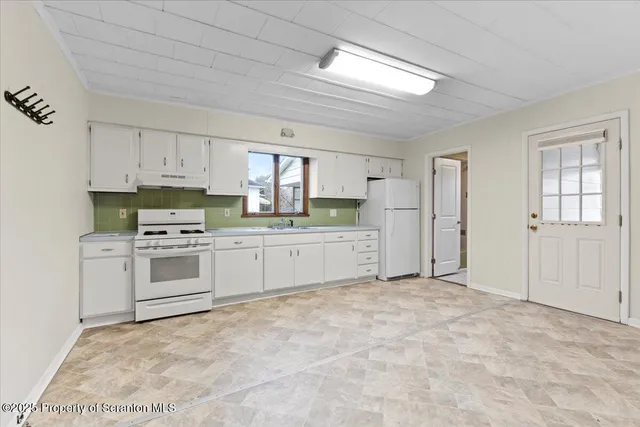 a kitchen with granite countertop a refrigerator and white cabinets