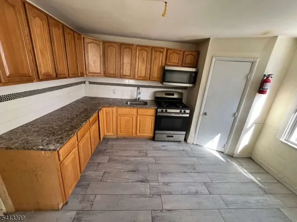 a kitchen with stainless steel appliances granite countertop a refrigerator a stove top oven and a sink with granite countertops