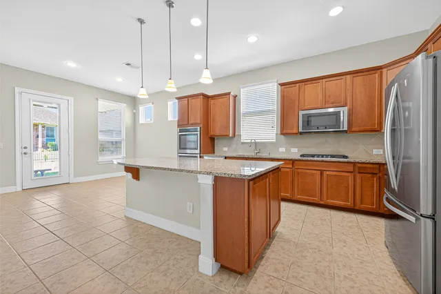 a large kitchen with a large counter top a sink a window and stainless steel appliances