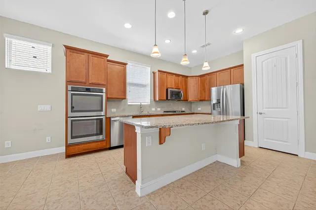 a kitchen with stainless steel appliances granite countertop a refrigerator a sink and a stove