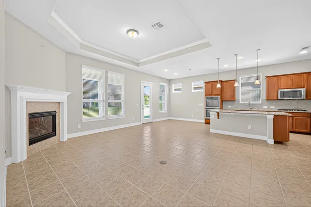 a view of an empty room with a window and kitchen view