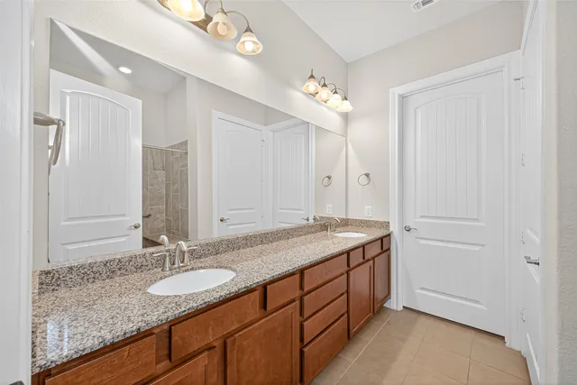 a bathroom with a granite countertop double vanity sink and a mirror