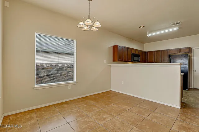 an empty room with chandelier fan and windows