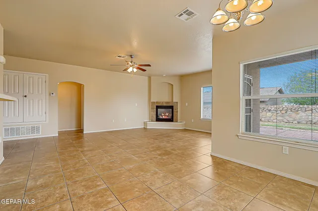 a view of an empty room with chandelier fan