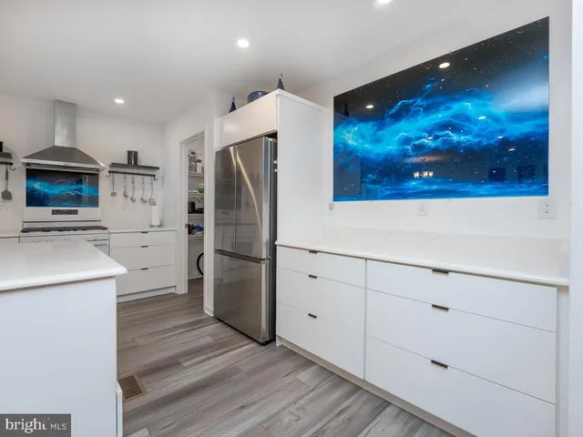 a kitchen with stainless steel appliances granite countertop a white stove top oven a dining table and chairs with wooden floor