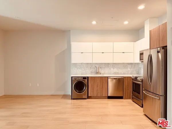 a kitchen with stainless steel appliances granite countertop a refrigerator a sink and a stove