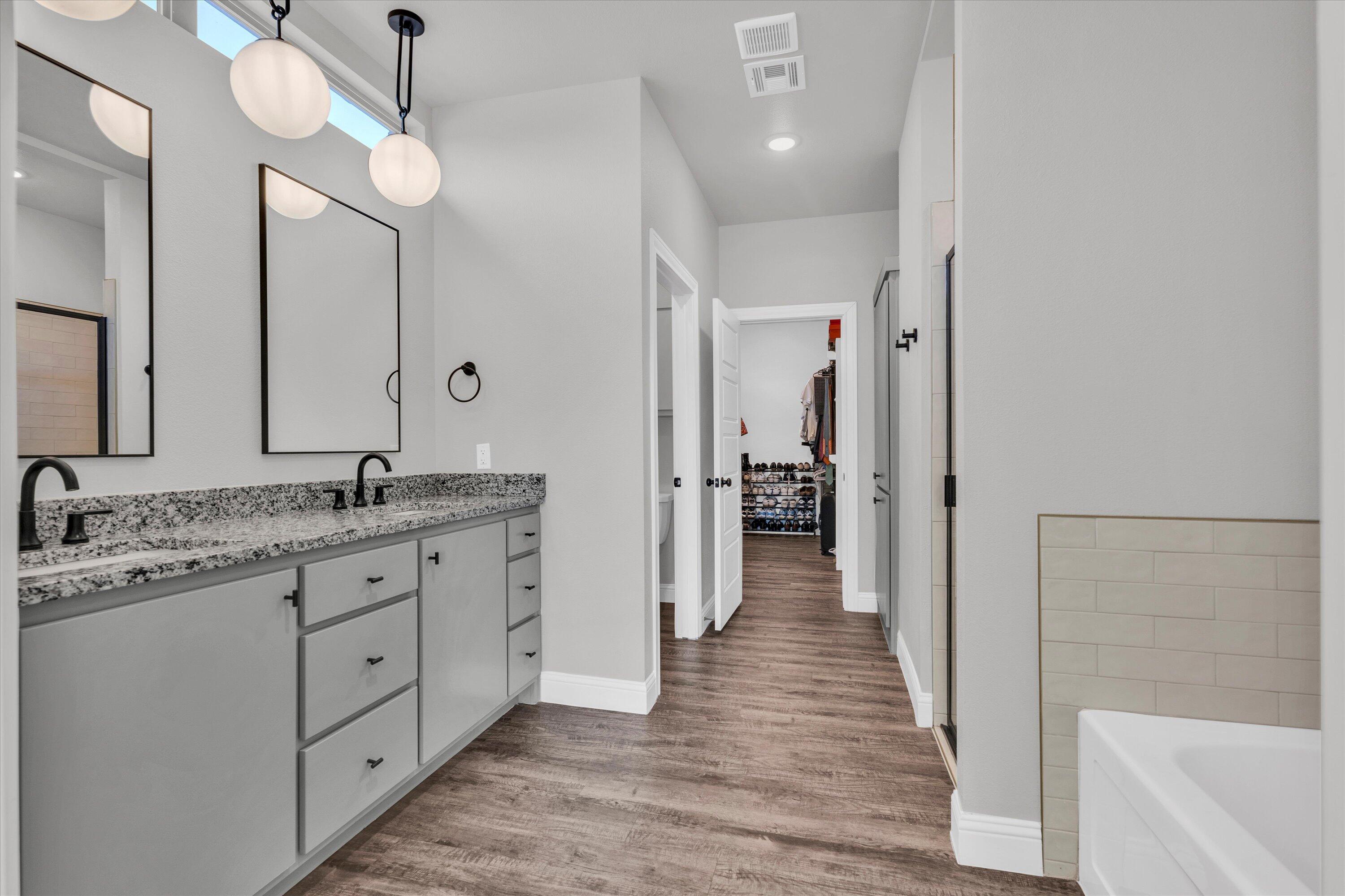 6803 52nd Street Lubbock, TX 79407 - Photo 15 of 34 a bathroom with a granite countertop sink a mirror and shower