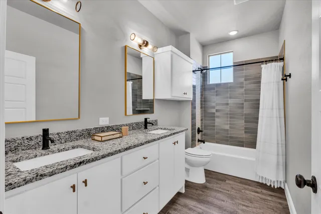 a bathroom with a granite countertop sink a toilet a mirror and shower