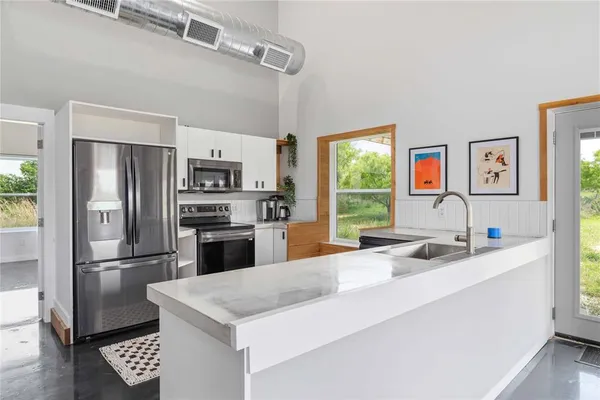 a kitchen with stainless steel appliances granite countertop a sink a refrigerator and a stove