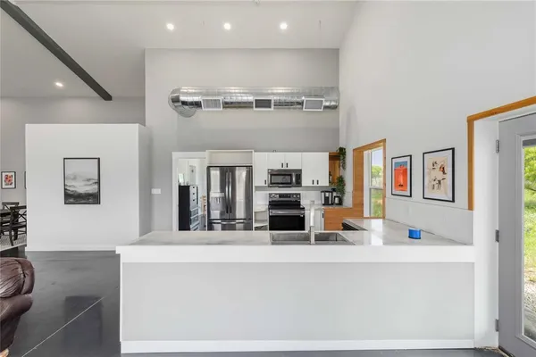 view of a living room kitchen with stainless steel appliances kitchen island granite countertop a refrigerator and a sink