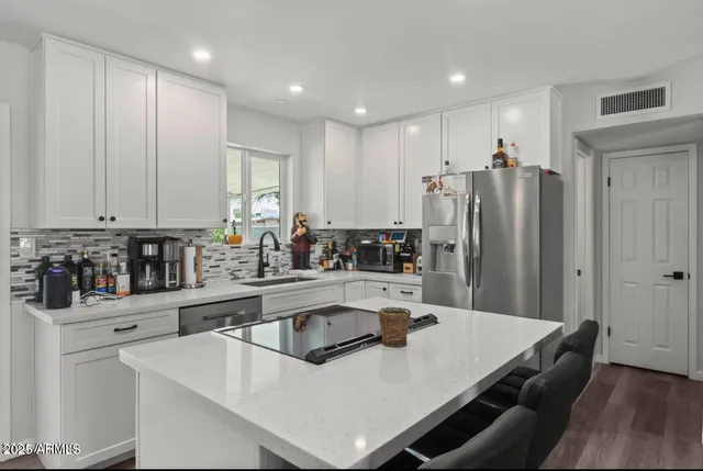 a kitchen with kitchen island a sink a stove a refrigerator and cabinets