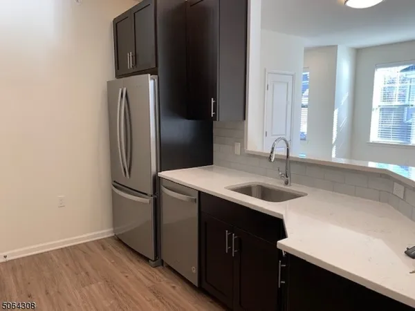 a kitchen with kitchen island granite countertop a sink and a refrigerator