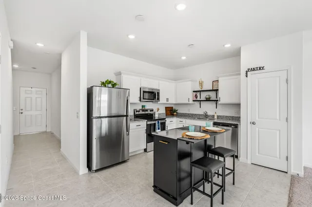 a kitchen with kitchen island a refrigerator a counter space and stainless steel appliances
