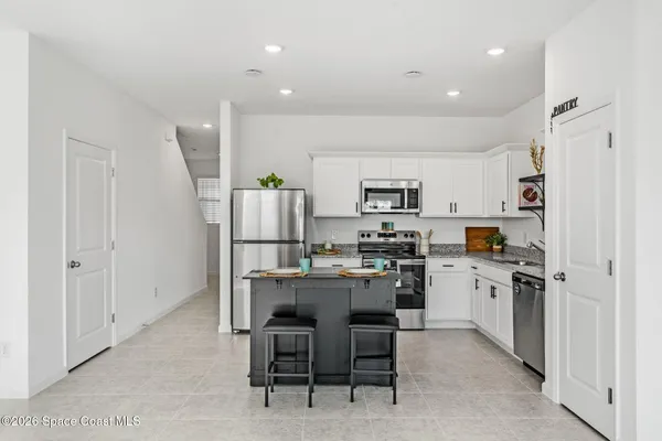a kitchen with kitchen island wooden cabinets and refrigerator