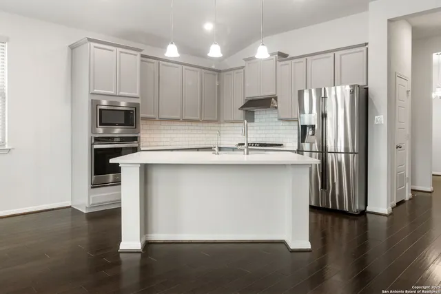 a kitchen with stainless steel appliances granite countertop a refrigerator a stove a sink and a microwave