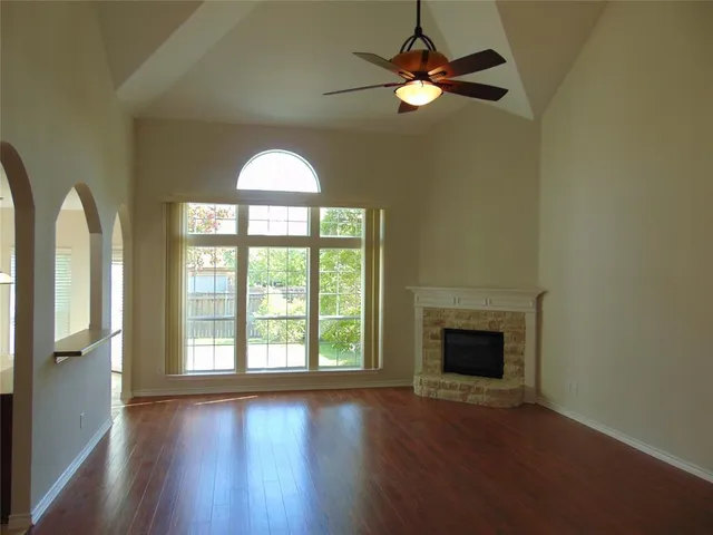 a view of empty room with wooden floor and fan