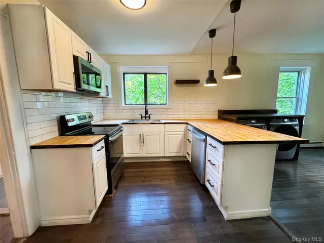 a kitchen with stainless steel appliances a sink a stove top oven a counter space and cabinets