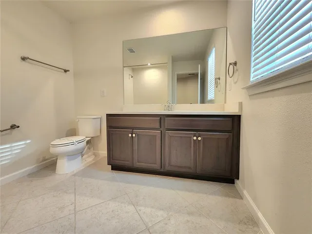 a spacious bathroom with a granite countertop sink a toilet and a mirror