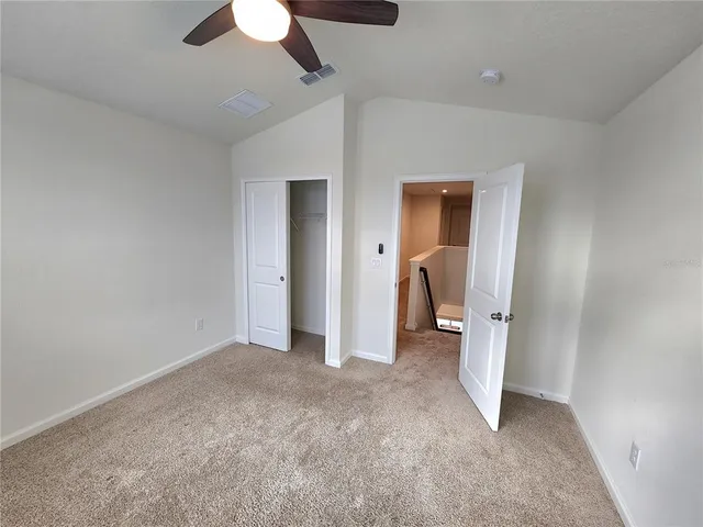 a view of a room with a ceiling fan and closet