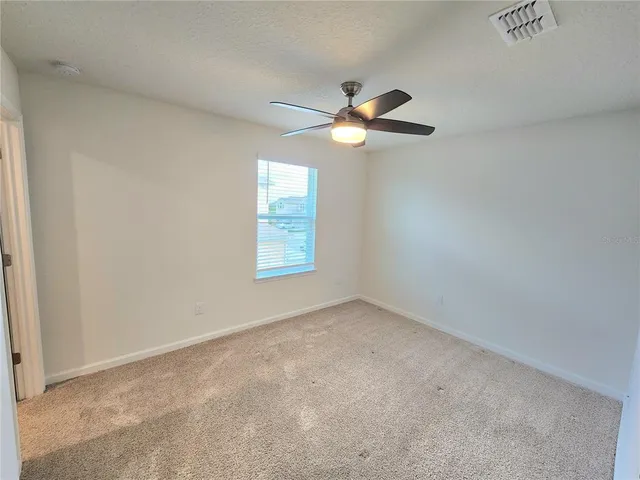 an empty room with windows and fan