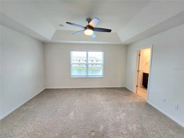an empty room with windows and ceiling fan