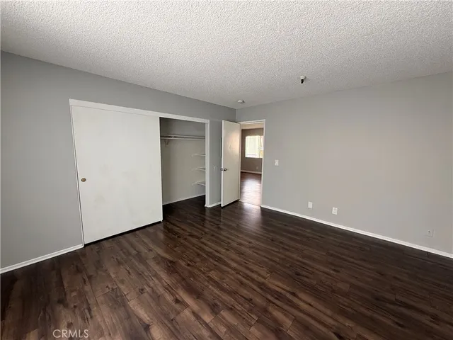 a view of an empty room with wooden floor and closet