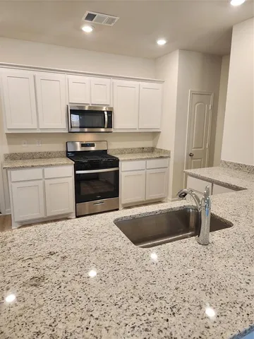 a kitchen with granite countertop a sink stove and refrigerator