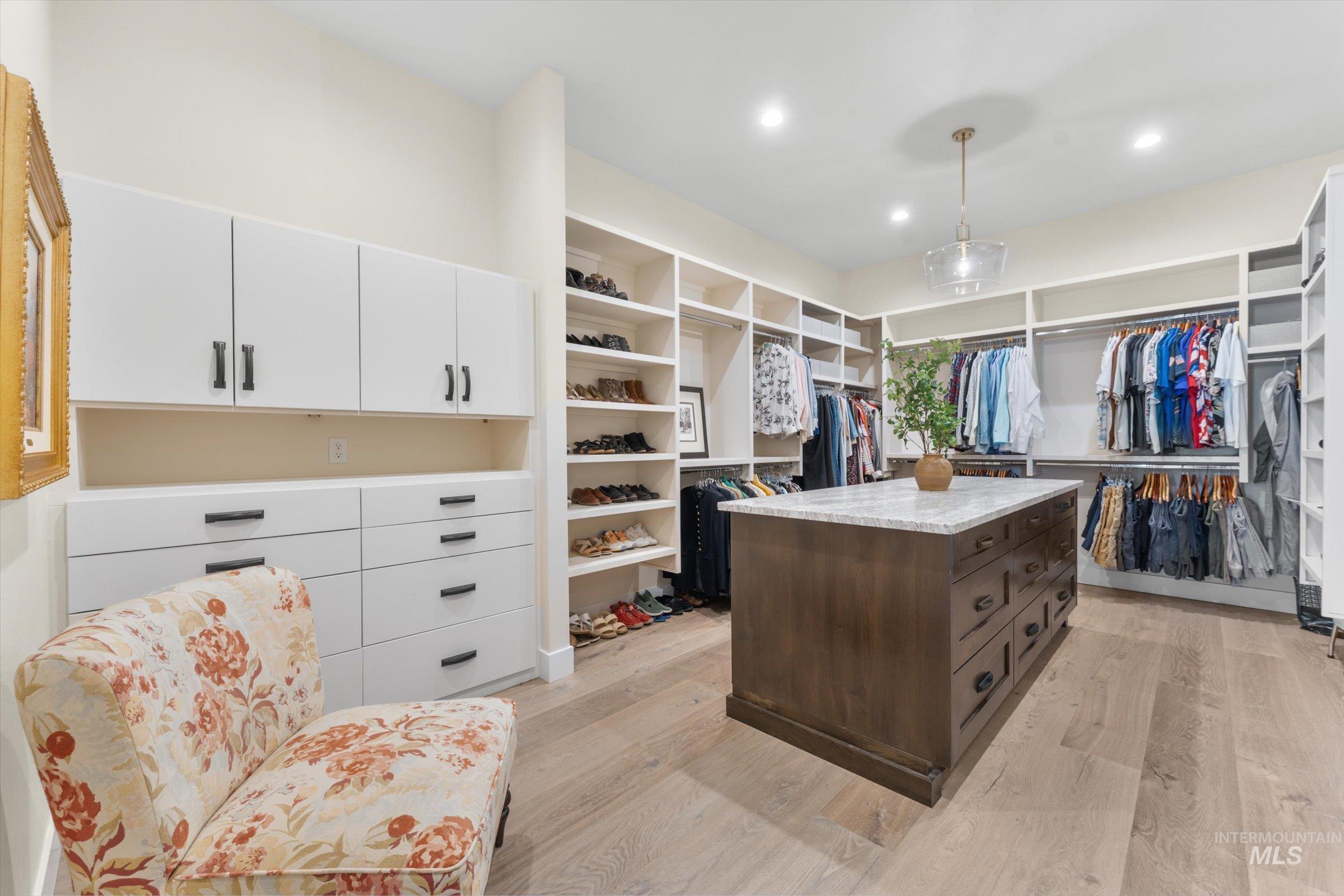 6585 South Pemberley Way Meridian, ID 83642 - Photo 27 of 43 Custom closet featuring extensive built-in storage, a central island with a stone countertop, recessed lighting, and wood-finish flooring