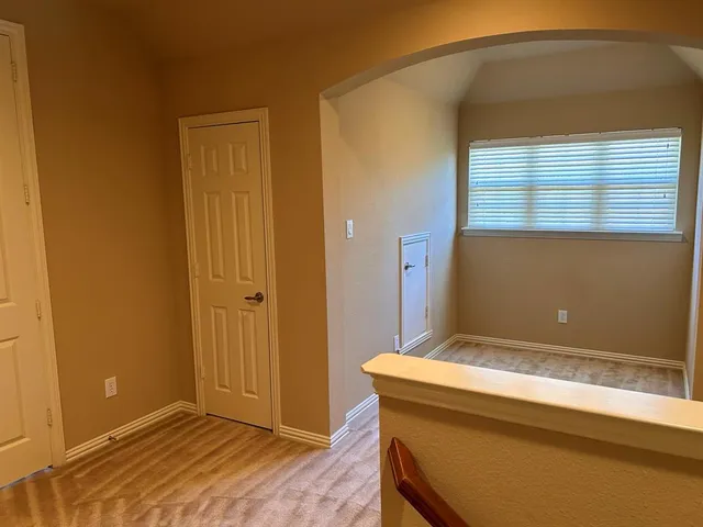 a view of an empty room with chandelier fan and wooden floor