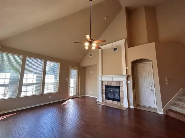 an empty room with wooden floor a fireplace and windows