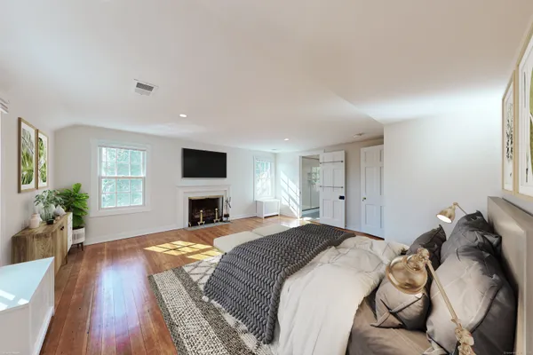 a spacious bedroom with a bed and wooden floor