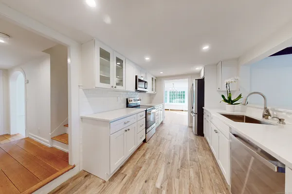 a large kitchen with stainless steel appliances granite countertop a lot of counter space and wooden floors