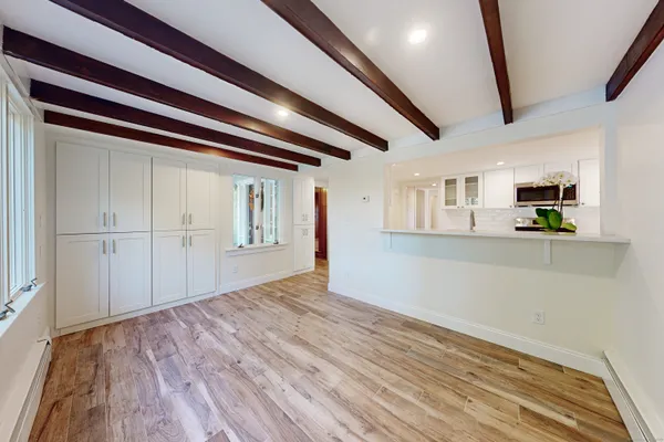 a view of an empty room with wooden floor and kitchen