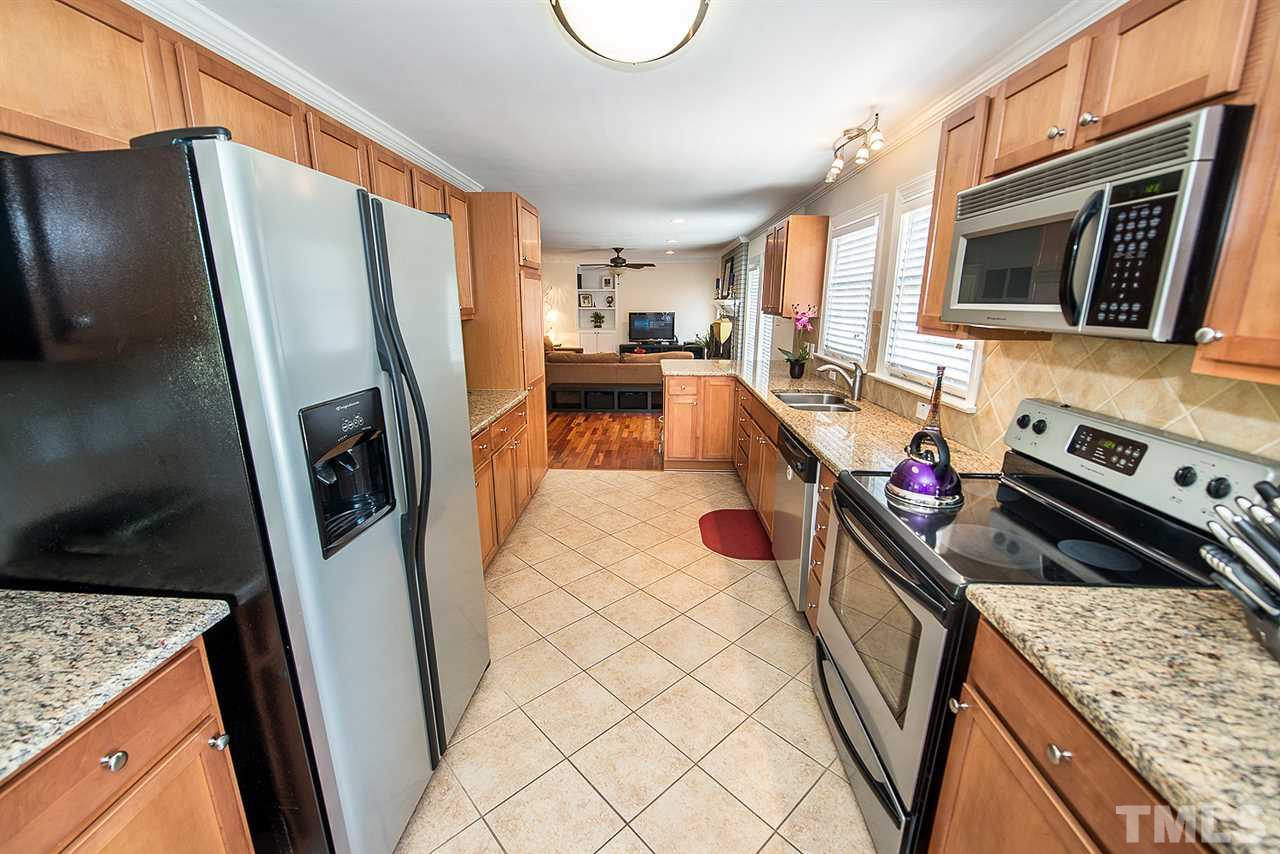6820 Lake Wheeler Road Raleigh, NC 27603 - Photo 7 of 25 Kitchen has granite, serving bar, tile backsplash, stainless appliances including a smooth top range, breakfast room and tile flooring.