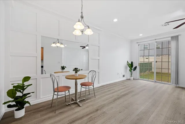 a view of a dining room with furniture a potted plant and wooden floor