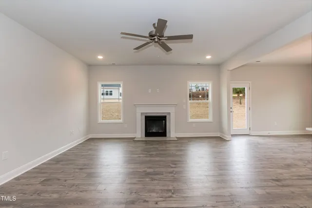 an empty room with wooden floor fireplace and windows