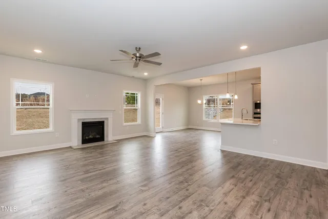 an empty room with windows fireplace and wooden floor