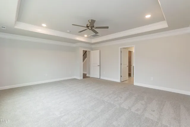 an empty room with chandelier fan and windows