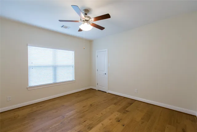an empty room with a window and a ceiling fan