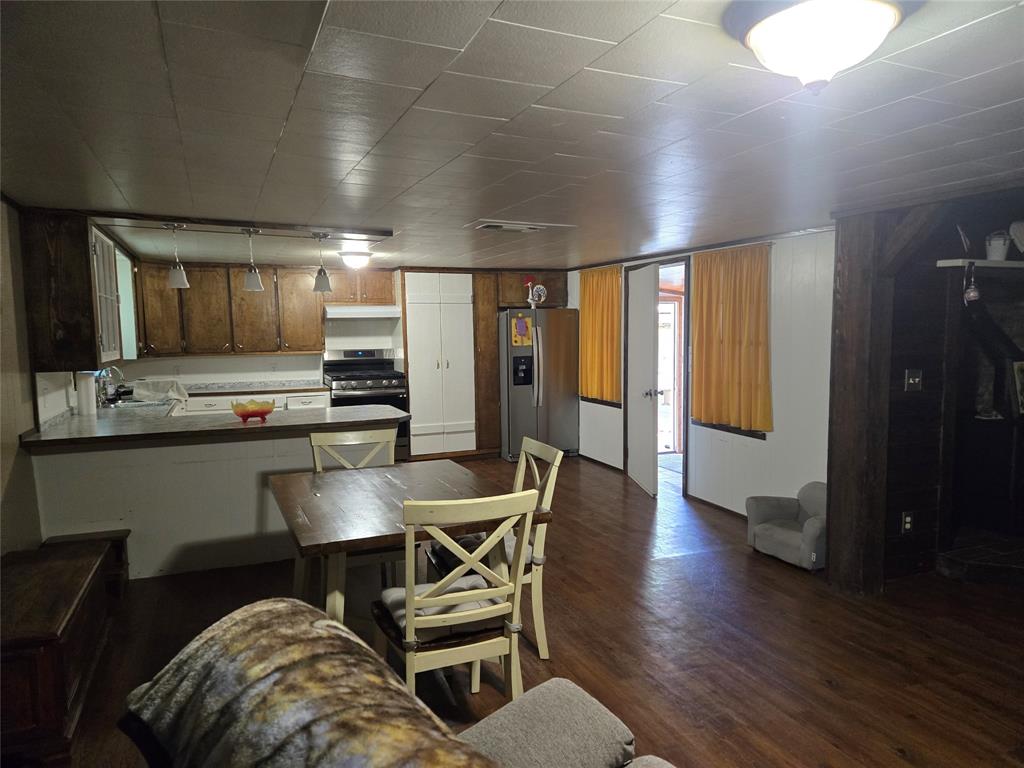 305 South Leon Street Gustine, TX 76455 - Photo 15 of 33 a kitchen with stainless steel appliances kitchen island granite countertop a stove a refrigerator a sink a dining table and chairs with wooden floor