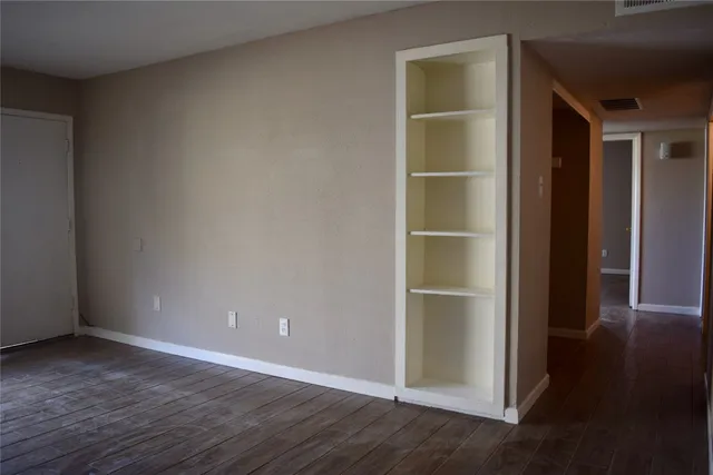 a view of an empty room with wooden floor and closet