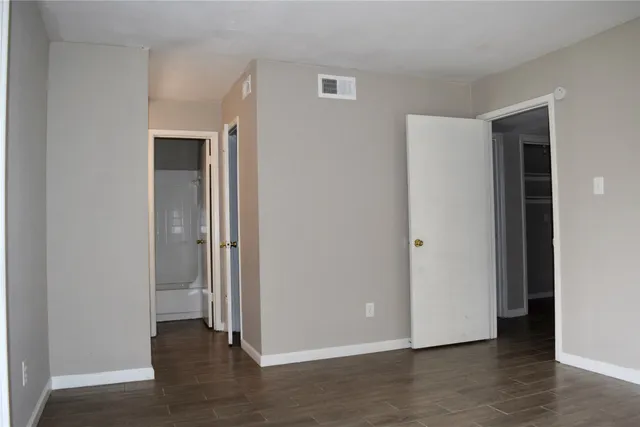 a view of an empty room with wooden floor & closet