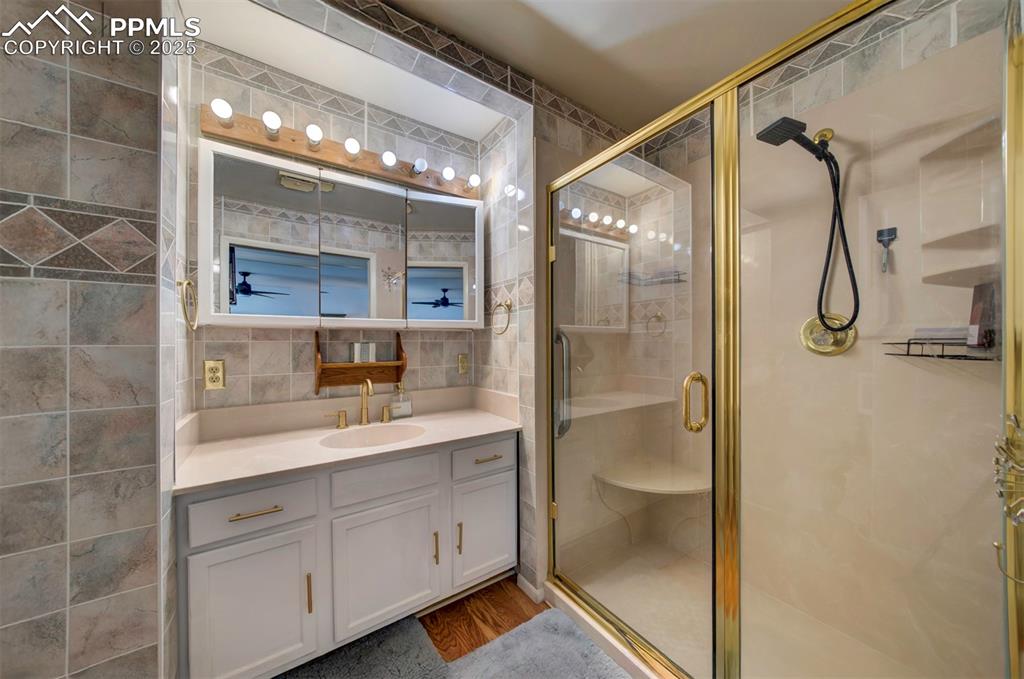 3710 Windflower Circle Colorado Springs, CO 80918 - Photo 18 of 32 a bathroom with a granite countertop sink a mirror and a shower