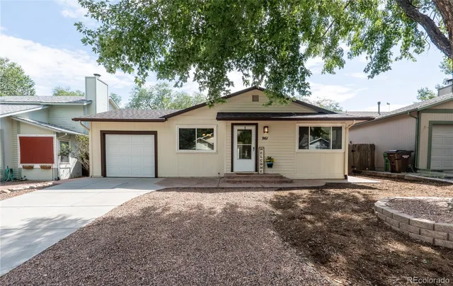 a front view of a house with yard and trees in the background