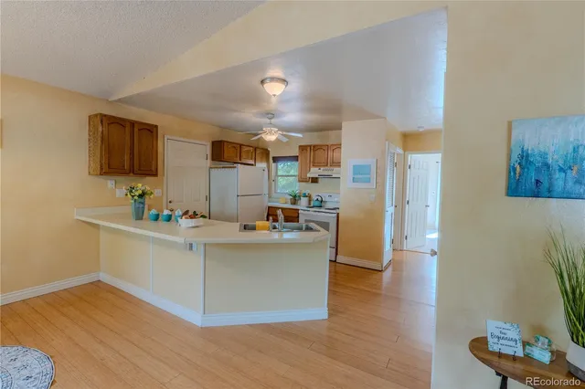 a living room with stainless steel appliances kitchen island a flat screen tv and a wooden floor