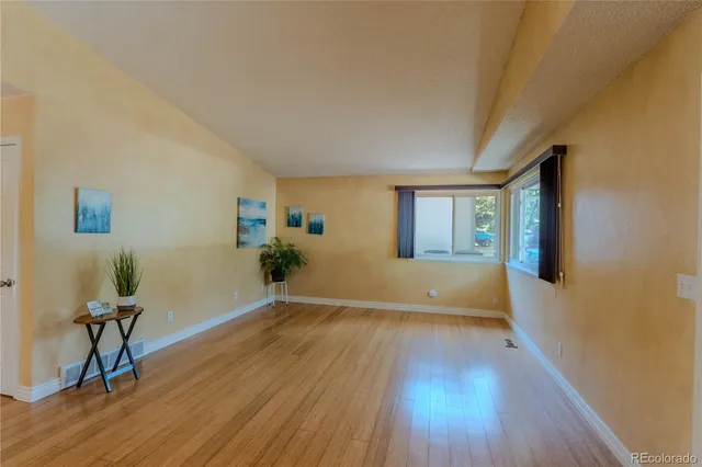 a view of an empty room with a window and wooden floor
