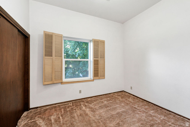 299 West Center Street, Unit 2 Logan, UT 84321 - Photo 19 of 46 Room featuring a window with louvered shutters, white walls, and brown carpeting