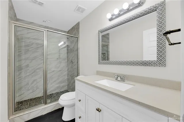 a bathroom with a granite countertop toilet a sink and a mirror