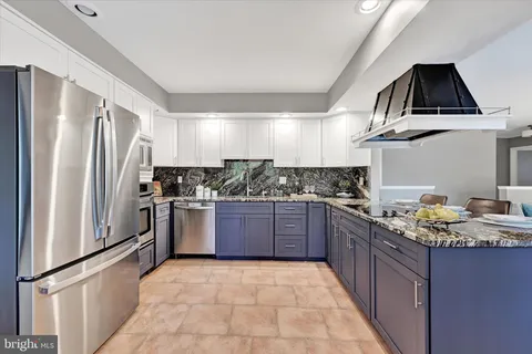 a kitchen with stainless steel appliances granite countertop a refrigerator a stove and a sink