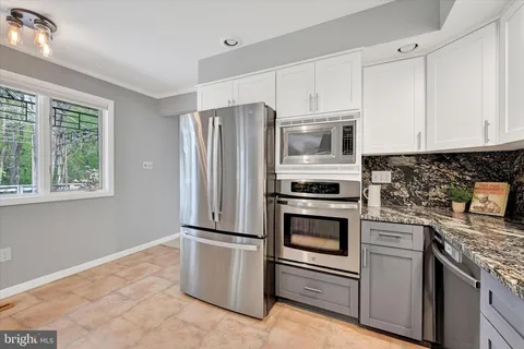 a kitchen with granite countertop white cabinets and stainless steel appliances